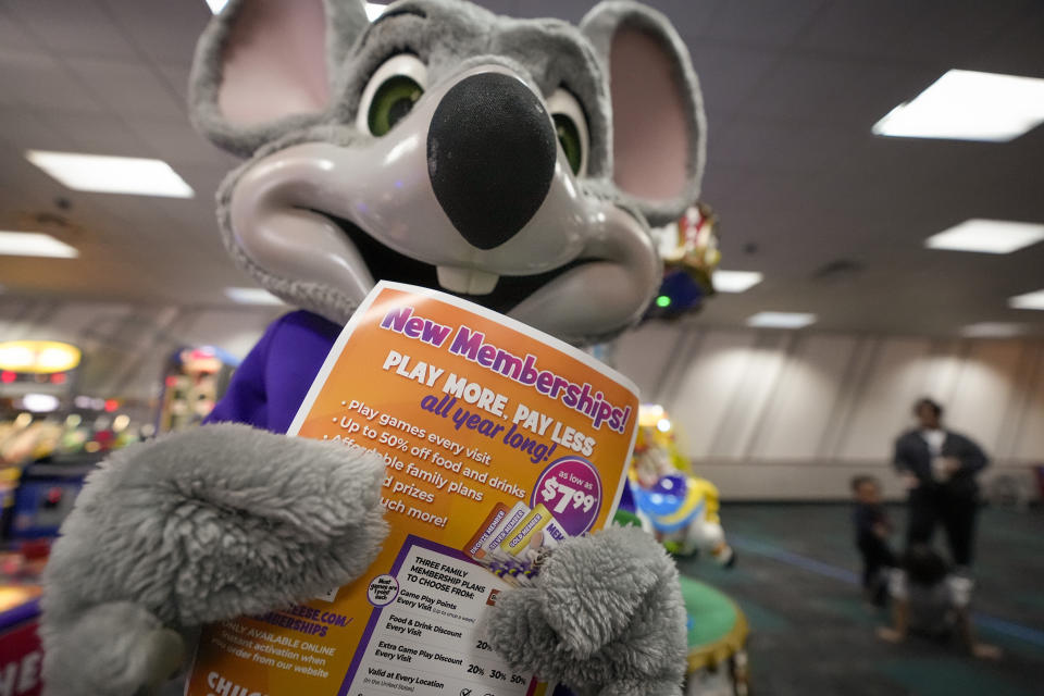 An employee dressed as Chuck E. Cheese holds a flyer advertising new memberships at a location Wednesday, March 13, 2024, in San Diego. Paid loyalty programs are all the rage in the restaurant and retail world. Looking for reliable sales in an unpredictable spending environment, more companies have extended their points-based loyalty tiers to making their most dependable customers feel valued for an up-front fee. (AP Photo/Gregory Bull)