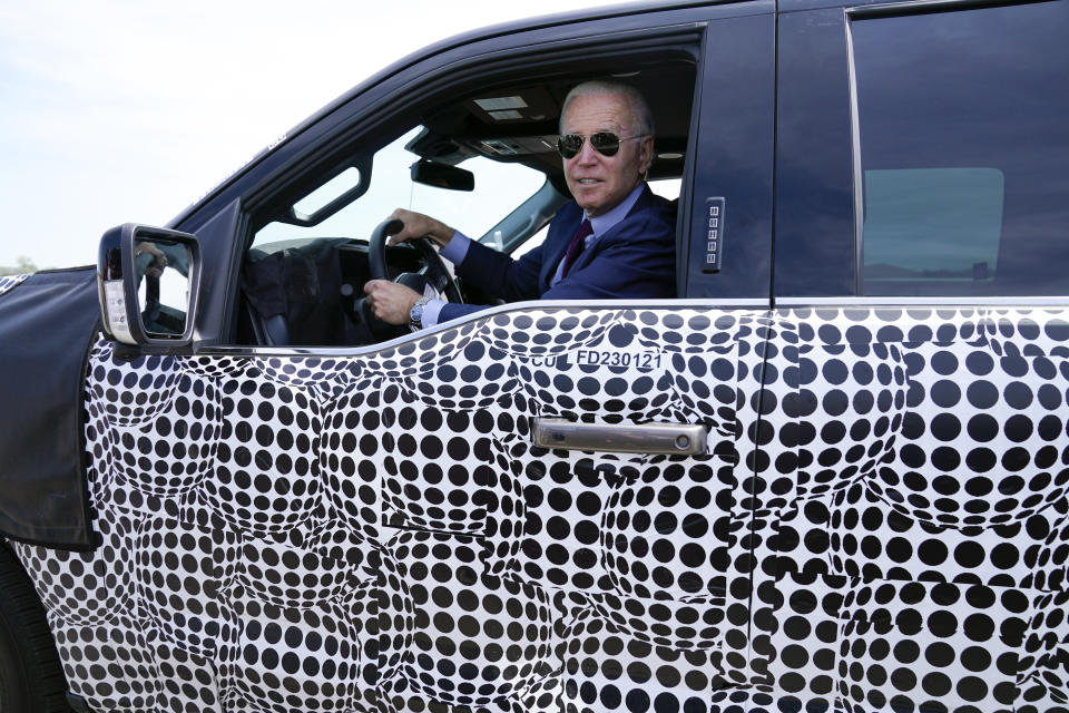 FILE - President Joe Biden stops to talk to the media as he drives a Ford F-150 Lightning truck at Ford Dearborn Development Center, May 18, 2021, in Dearborn, Mich. Biden, a self-described “car guy,'' often promises to lead by example by moving swiftly to convert the sprawling federal fleet to zero-emission electric vehicles. But efforts to help meet his ambitious climate goals by eliminating gas-powered vehicles from the federal fleet have lagged. (AP Photo/Evan Vucci, File)