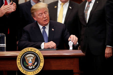 U.S. President Donald Trump holds a space astronaut toy as he participates in a signing ceremony for Space Policy Directive at the White House in Washington D.C., U.S. December 11, 2017. REUTERS/Carlos Barria