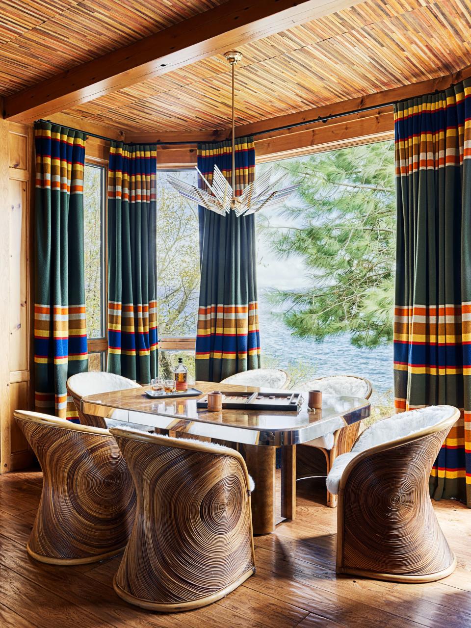 Vintage rattan barrel chairs surround the game table in the study. Curtains fabricated from Pendleton blankets; Milo Baughman game table; vintage Sciolari glass chandelier; on ceiling, woven wall covering by Élitis.