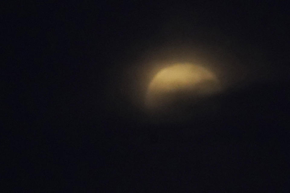 The moon rises behind cloud, as seen from Kawasaki near Tokyo, before a total lunar eclipse starts Wednesday, May 26, 2021. (AP Photo/Shuji Kajiyama)