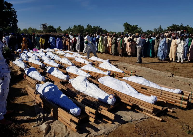 Men gather near dead bodies of people who were killed by militant attack, during a mass burial at Zabarmari