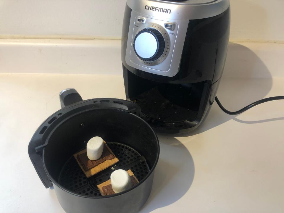 two smores set up in an air fryer basket in front of the air fryer