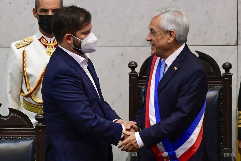 Sebastian Piñera saluda a Gabriel Boric al entregarle la banda presidencial, el 11 de marzo de 2022, en Valparaíso. (MARTIN BERNETTI / AFP)