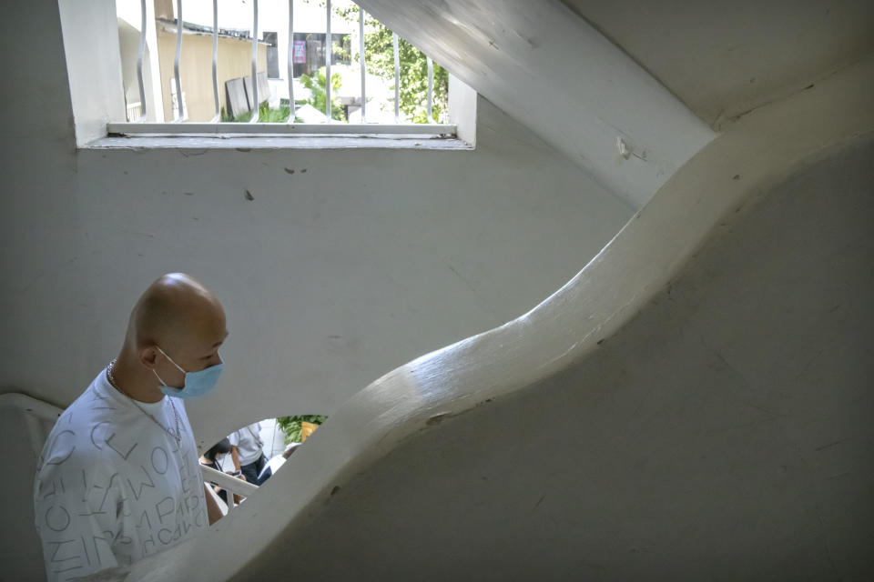 A man wearing a face mask to help protect against the spread of COVID-19 walks down a staircase at a shopping complex in Beijing, Tuesday, Aug. 17, 2021. (AP Photo/Mark Schiefelbein)