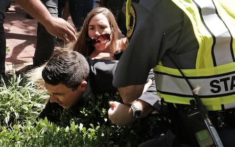 Jason Kessler is helped by police after being tackled by a woman  - Credit:  REUTERS