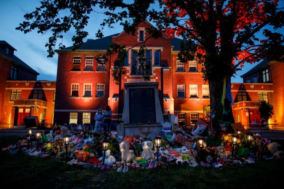 A makeshift memorial to honour the 215 children whose remains have been discovered buried near the facility is seen as orange light drapes the facade of the former Kamloops Indian Residential School in Kamloops, British Columbia, Canada, on June 2, 2021.<span class="copyright">Cole Burston—AFP via Getty Images</span>