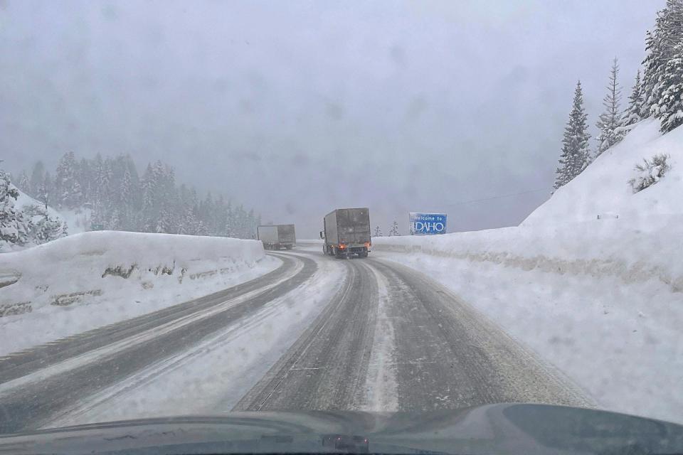 Snowy winter driving conditions entering Idaho through the mountain pass along Interstate 90