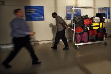 FILE PHOTO - A worker pulls a car with luggages while passengers arrive to the Newark Liberty International Airport in Newark, New Jersey November 15, 2012. REUTERS/Eduardo Munoz