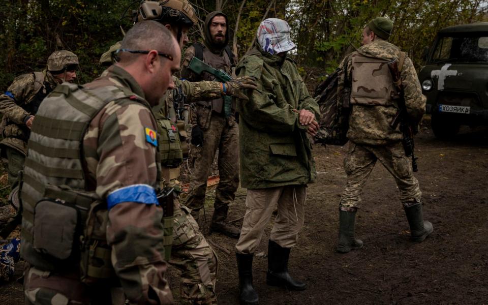 Ukrainian soldiers escort a suspected Russian spy on to the west bank of the Siverskyi Donets River, near Lyman, Ukraine - Nicole Tung/Nytns