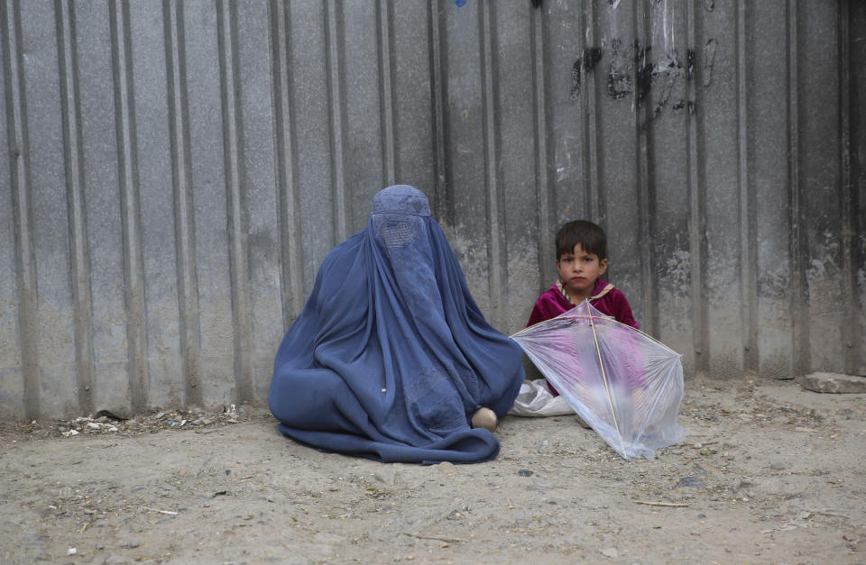 A woman waits to receive alms with her daughter during holy fasting month of Ramadan in Kabul, Afghanistan, Saturday, May 2, 2020. Muslims across the world are observing Ramadan when the faithful refrain from eating, drinking and smoking from dawn to dusk. (AP Photo/Rahmat Gul)