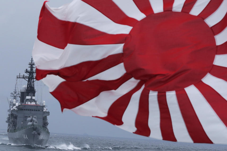 FILE - In this Oct. 14, 2012, file photo, Japan Maritime Self-Defense Force (JMSDF) escort ship "Kurama," left, navigates behind destroyer "Yudachi," with a rising sun flag, during a fleet review in water off Sagami Bay, south of Tokyo. Japan’s “rising sun” flag is raising anger at the Olympics, with some of the host nation’s neighbors calling for it to be banned during the Tokyo Games, which start Friday, July 23, 2021. (AP Photo/Itsuo Inouye, File)