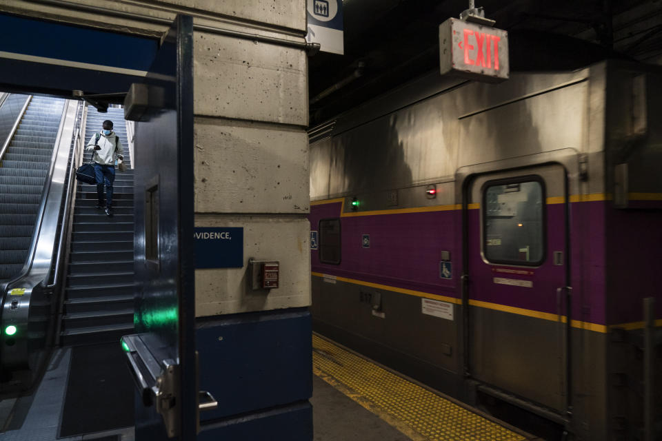 A passenger descends a staircase to board an Amtrak train as a commuter train heading to Boston leaves the station at right, Friday, Nov. 20, 2020, in Providence, R.I. With the coronavirus surging out of control, the nation's top public health agency pleaded with Americans not to travel for Thanksgiving and not to spend the holiday with people from outside their household. (AP Photo/David Goldman)