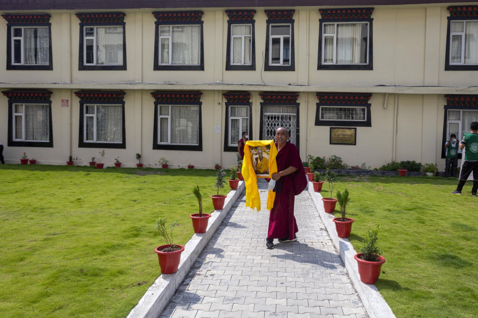 An exile Tibetan monk carries a portrait of his spiritual leader the Dalai Lama as he celebrates the 86th birthday of the Tibetan leader in Dharmsala, India, Tuesday, July 6, 2021. The Dalai Lama made the hillside town of Dharmsala his headquarters after a failed uprising against Chinese rule in 1959. (AP Photo/Ashwini Bhatia)