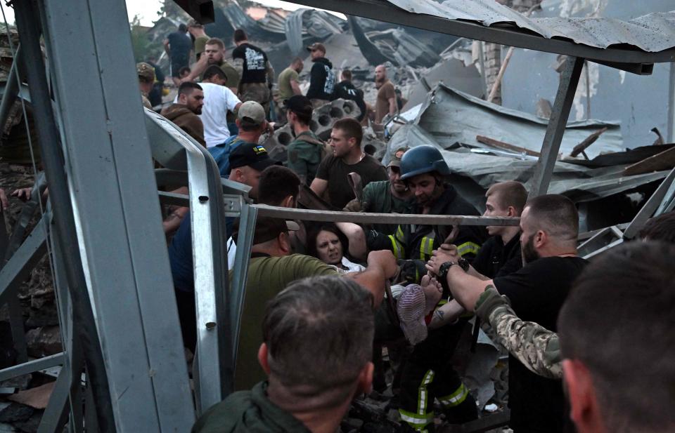 Rescuers and volunteers carry a rescued woman from the rubble after Russian missile strike hit a restaurant and several houses in Kramatorsk, eastern Ukraine, on June 27, 2023.