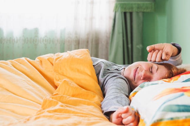 A woman stretches happily as she wakes in a bright room