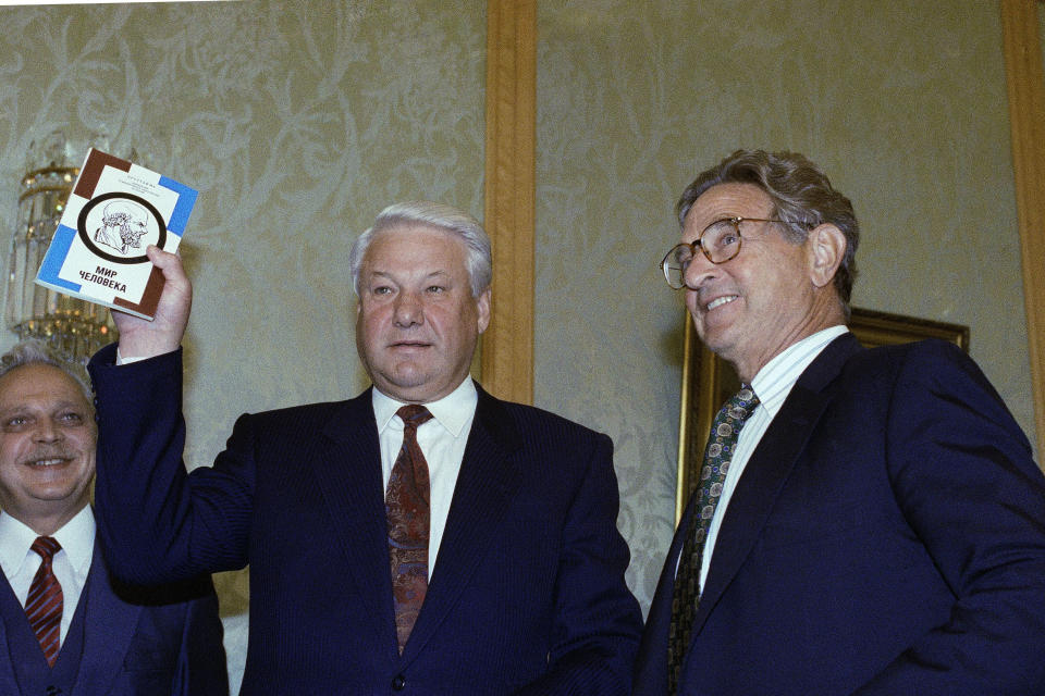 FILE - In this Sept. 23, 1993 file photo, Russian President Boris Yeltsin holds up a book he was given by U.S. financier George Soros, right, during their meeting at the Kremlin on Sept. 23, 1993. Soros has given millions of dollars to help post-Communist countries in Eastern Europe. The mail bomb that showed up in the mail box of billionaire investor and philanthropist George Soros on Oct. 22, 2018 is a reminder of his place as one of the far right’s most hated boogeymen. (AP Photo, File)