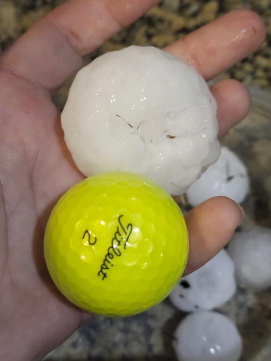 In this image provided by Randy Smith, a large chunk of hail is compared to the size of a golf ball, Wednesday night, March 13, 2024, in Shawnee, Kan. Volatile weather was honing in on parts of Kansas and Missouri Wednesday night, with some storms bringing massive chunks of hail. (Randy Smith via AP)