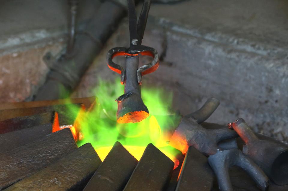 Jeff Becker, of Coopermill Bronze Works, puts a piece of bronze into the bronze work's furnace. In time, the bronze will be part of an 8-foot-tall statue of Massillon football mascot Obie.