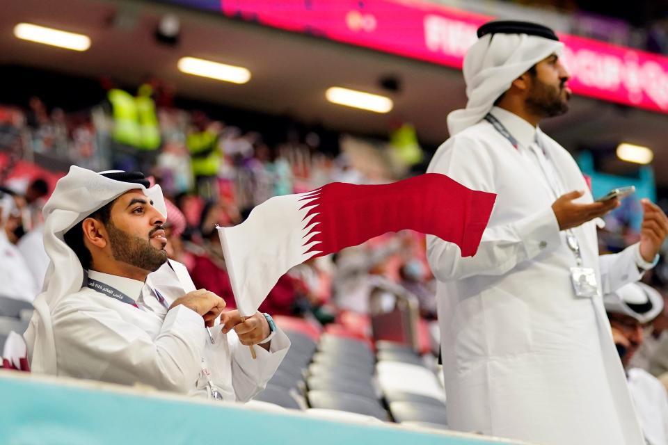 A fan waves a Qatar flag before a group stage match during the 2022 FIFA World Cup between Qatar and Ecuador at Al Bayt Stadium on Sunday, Nov. 20, 2022.