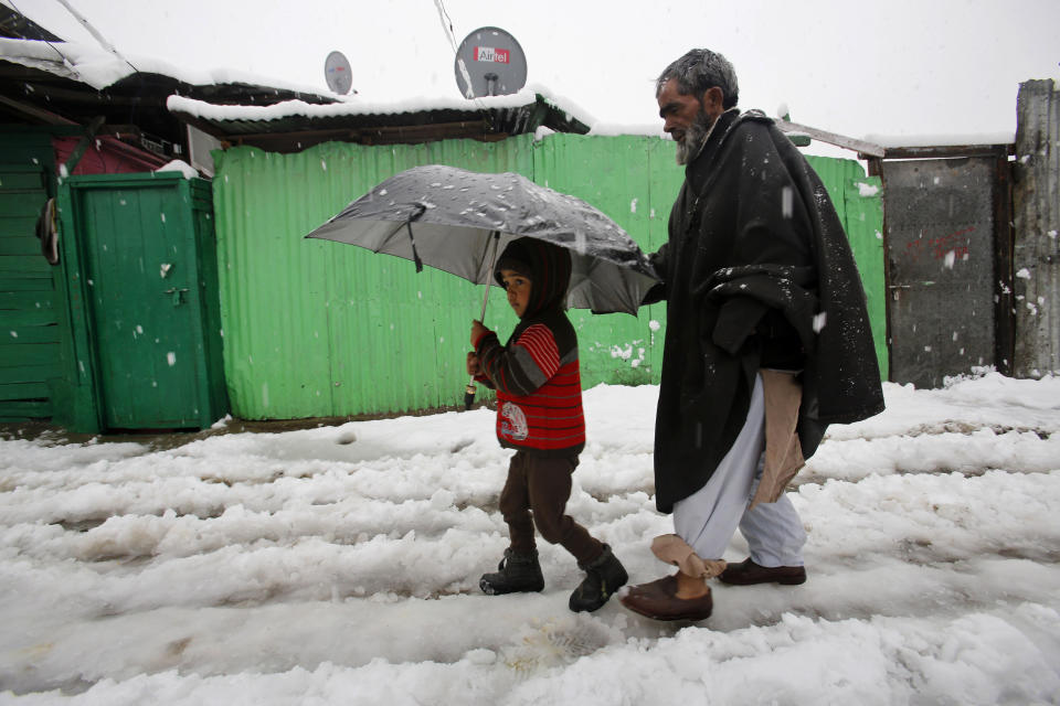 A Kashmiri boy and a man walk in the snow in Srinagar, India, Tuesday, March 11, 2014. The Kashmir valley was Tuesday cut off from rest of India due to heavy snowfall. (AP Photo/Mukhtar Khan)