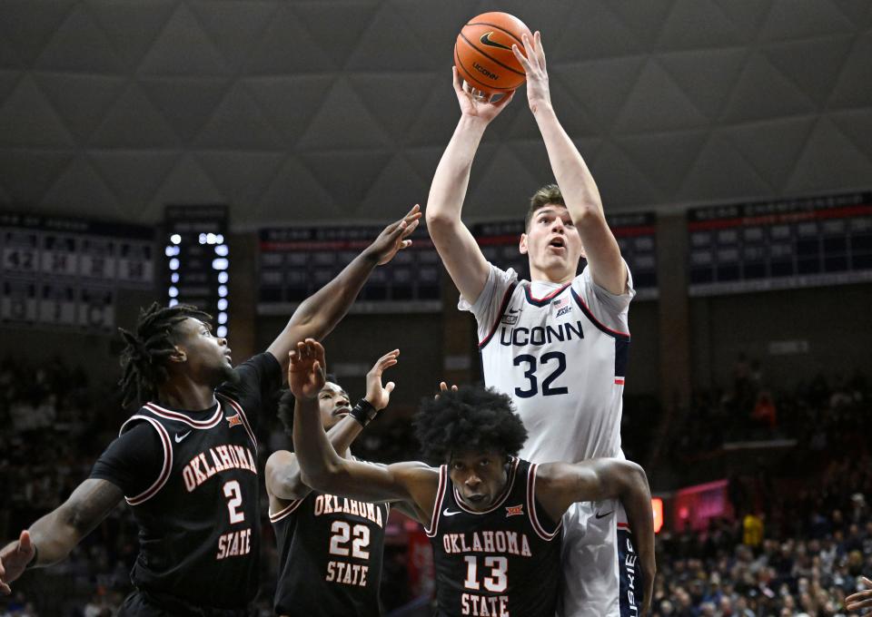 Connecticut's Donovan Clingan (32) shoots over Oklahoma State's Chris Harris Jr. (2), Kalib Boone (22) and Quion Williams (13) in the first half of an NCAA college basketball game, Thursday, Dec. 1, 2022, in Storrs, Conn. (AP Photo/Jessica Hill)