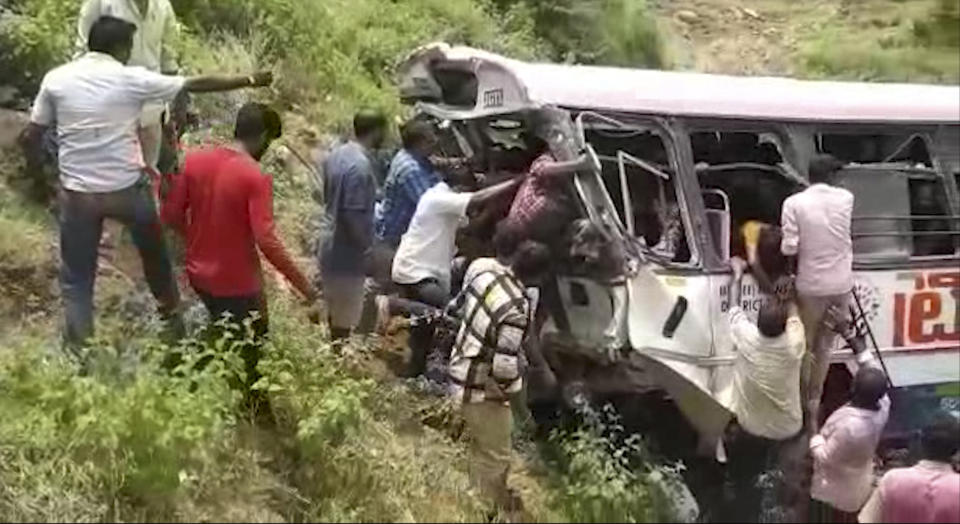 In this grab made from video provided by KK Productions, rescuers pull out passengers from a bus that fell into a gorge in Jagtiyal district of Telangana, India, Tuesday, Sept. 11, 2018. The bus was carrying pilgrims from a Hindu temple in the hills of south India when it plunged off a road killing several people (KK Production via AP)