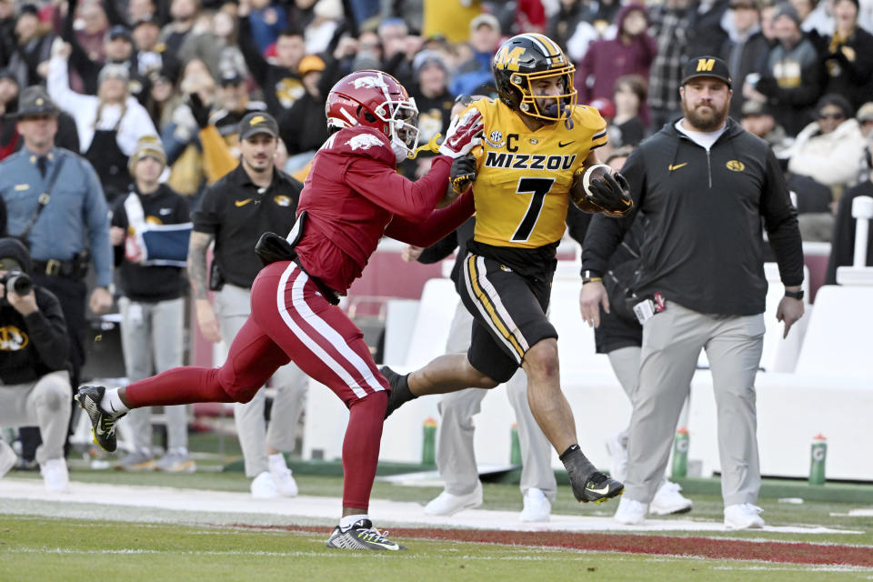 Missouri running back Cody Schrader (7) is knocked out of bounds by Arkansas defensive back Lorando Johnson (1) during an NCAA college football game Friday, Nov. 24, 2023, in Fayetteville, Ark. (AP Photo/Michael Woods)