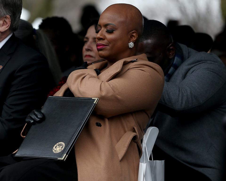 U.S. Rep. Ayanna Pressley reaches back to hold hands with a person standing behind her during the unveiling ceremony Friday of "The Embrace," a sculpture dedicated to the late Rev. Martin Luther King Jr. and Coretta Scott King on Boston Common.