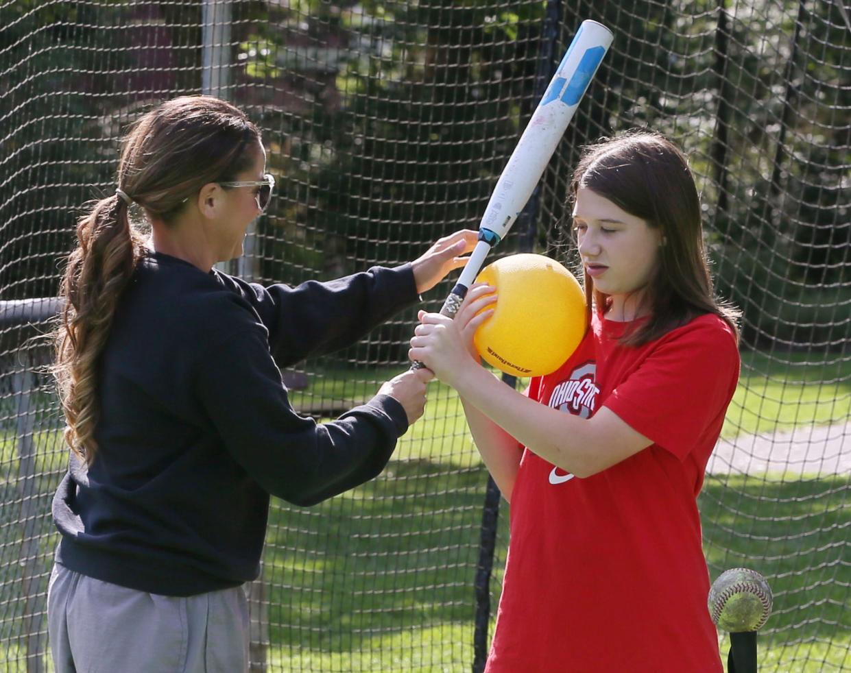 Tracee McCoy-Jenkins, an Ellet High School, University of Akron and Akron Racers softball legend, helps her student, Brynn, 12, in the batting cages at Stein Field at Indian Hills Park in Tallmadge on Aug. 22.