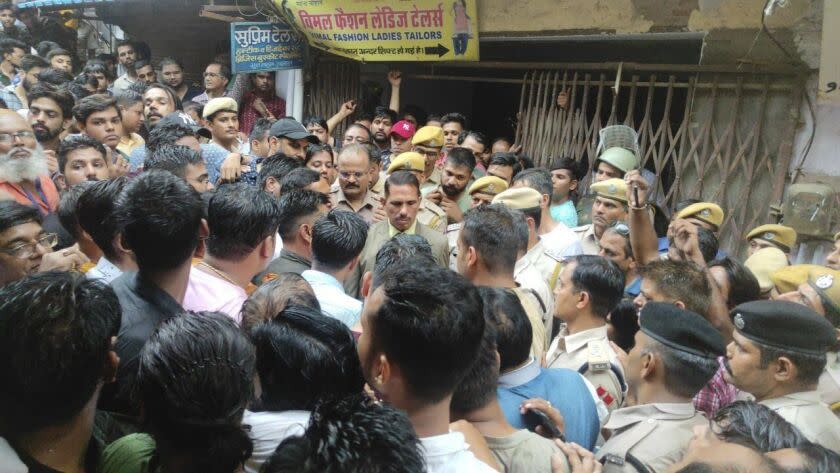 A crowd gathers outside the shop of a tailor who was killed, as police investigate in Udaipur, India, Tuesday, June 28, 2022. Mobile internet services and large gatherings have been restricted in India's western Udaipur city, a day after police arrested two Muslim men accused of killing a Hindu tailor in a suspected religious attack. The Hindu man, Kanhaiya Lal, was stabbed multiple times inside his tailoring shop Tuesday by two cleaver-wielding men who also filmed the attack, news agency Press Trust of India reported. (AP Photo).