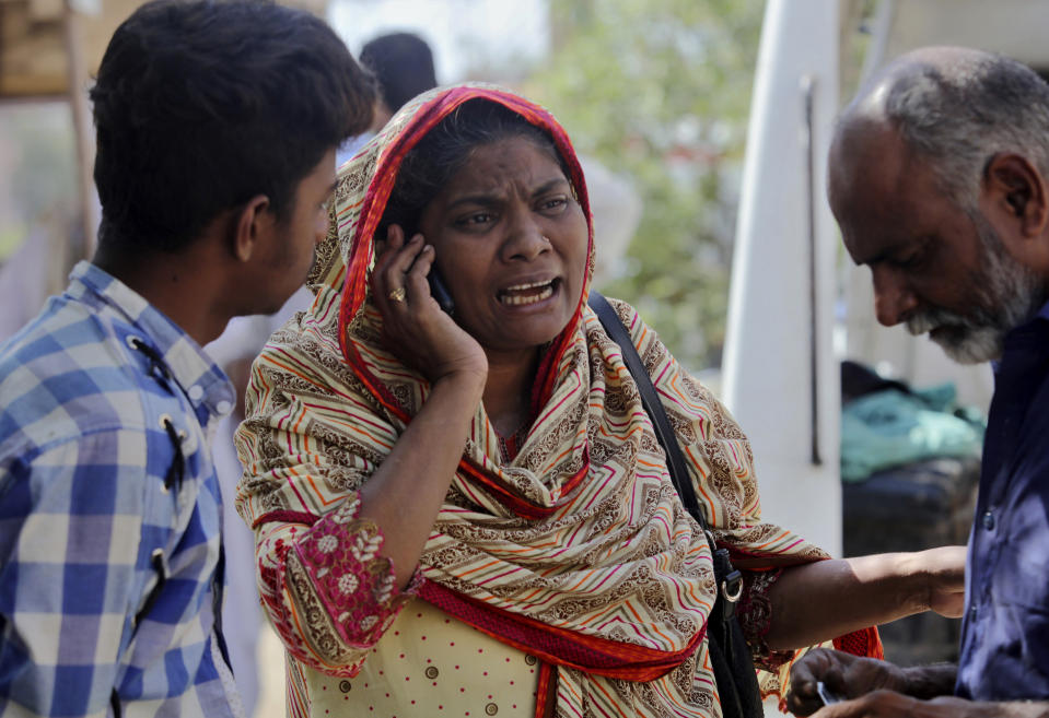 A woman mourns while talking on cell phone after she identified a body of her family member, who was killed in the Friday's plane crash, at a morgue in Karachi, Pakistan, Saturday, May 23, 2020. An aviation official says a passenger plane belonging to state-run Pakistan International Airlines carrying passengers and crew has crashed near the southern port city of Karachi. (AP Photo/Fareed Khan)