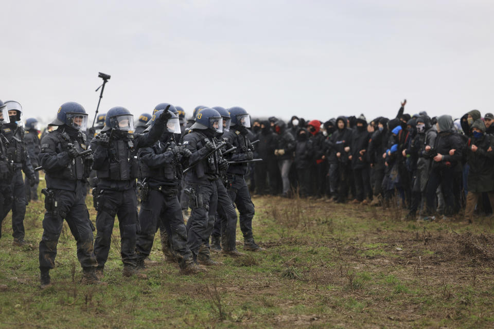 Police officers form a line to block demonstrators on the edge of the opencast lignite mine Garzweiler at the village Luetzerath near Erkelenz, Germany, Saturday, Jan. 14, 2023. ( Oliver Berg/dpa via AP)