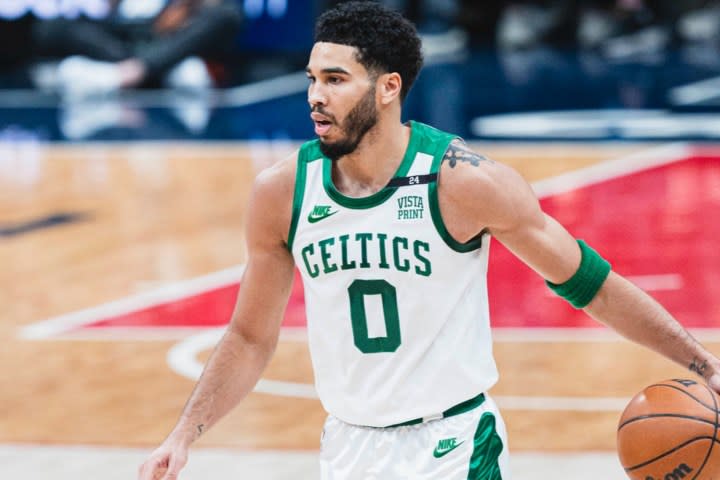 Jayson Tatum dribbles a ball on a basketball court.