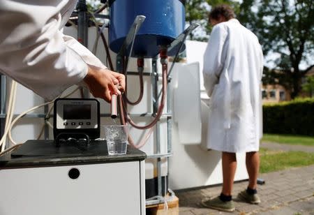 Belgian scientists Marjolein Vanoppen and Sebastiaan Derese demonstrate the use of a machine that turns urine into drinkable water and fertilizer using solar energy, at the University of Ghent, Belgium, July 26, 2016. REUTERS/Francois Lenoir