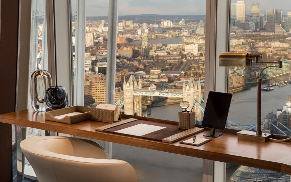 sleek wooden desk overlooking floor-to-ceiling windows through which you can see the Thames and Tower of London - Richard Waite 