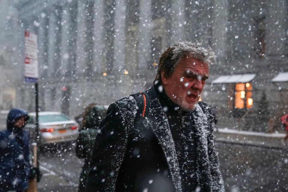 Pedestrians walk through the falling snow in the Financial District, January 30, 2019 in New York City.