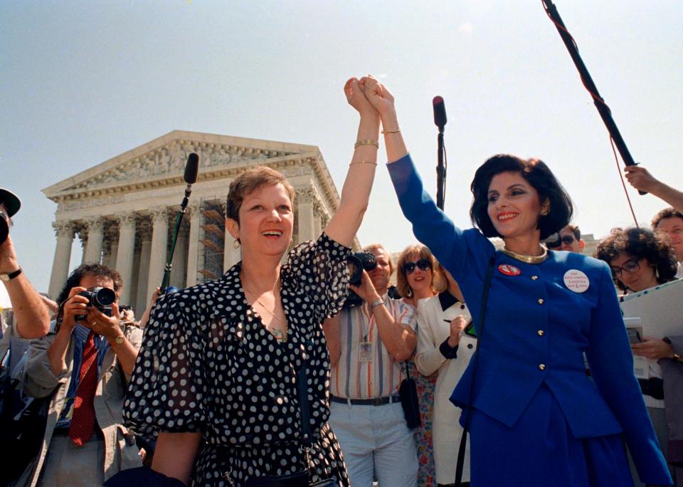 Norma McCorvey, Jane Roe in the 1973 court case, left, and her attorney Gloria Allred hold hands as they leave the Supreme Court building in Washington after sitting in while the court listened to arguments in a Missouri abortion case, Apr. 26, 1989. A leaked draft of a U.S. Supreme Court decision suggests the country's highest court could be poised to overturn the constitutional right to abortion. (AP Photo/J. Scott Applewhite, File)