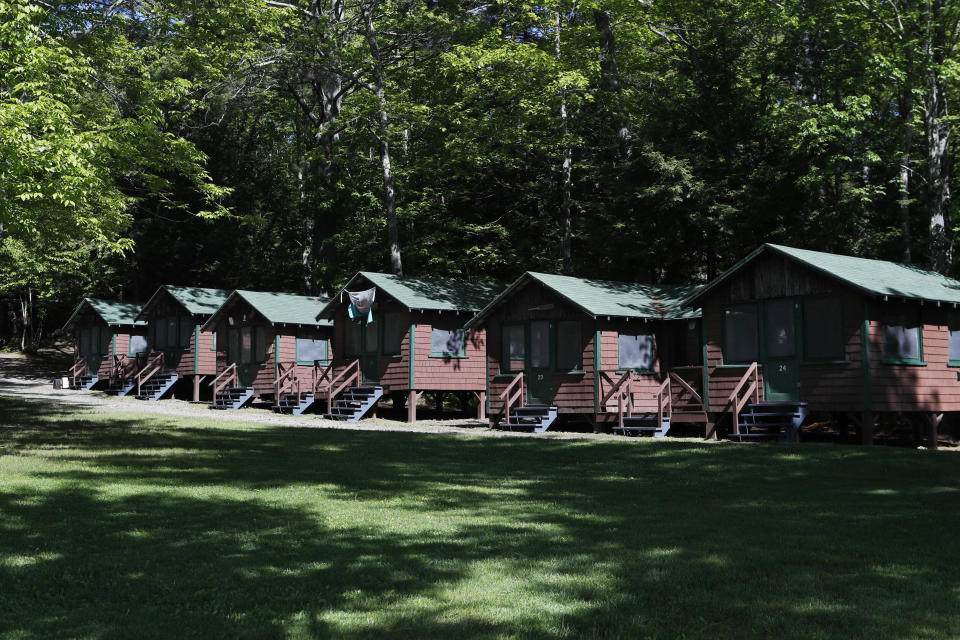 FILE - This Thursday, June 4, 2020 file photo shows a row of cabins at a summer camp in Fayette, Maine. On Friday, May 28, 2021, the Centers for Disease Control and Prevention posted guidance saying kids at summer camps can skip wearing masks outdoors, with some exceptions. Children who aren’t fully vaccinated should still wear masks outside when they’re in crowds or in sustained close contact with others – and when they are inside, and fully vaccinated kids need not wear masks indoors or outside, the CDC says. (AP Photo/Robert F. Bukaty, File)