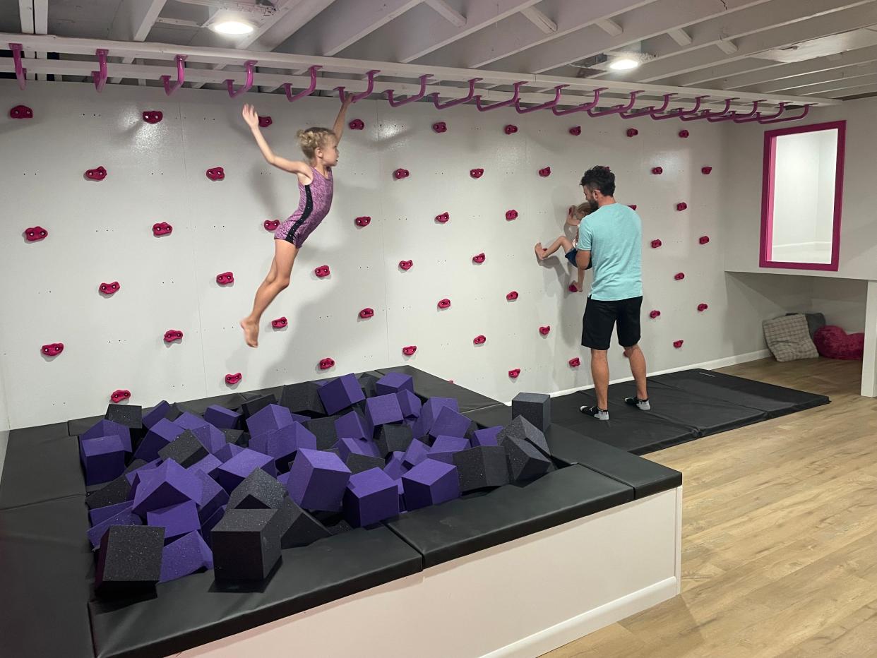 Everlie Shiprke (on monkey bars) swings through her family's new at-home gymnastics gym from Make-a-Wish Wisconsin and Riley Construction.