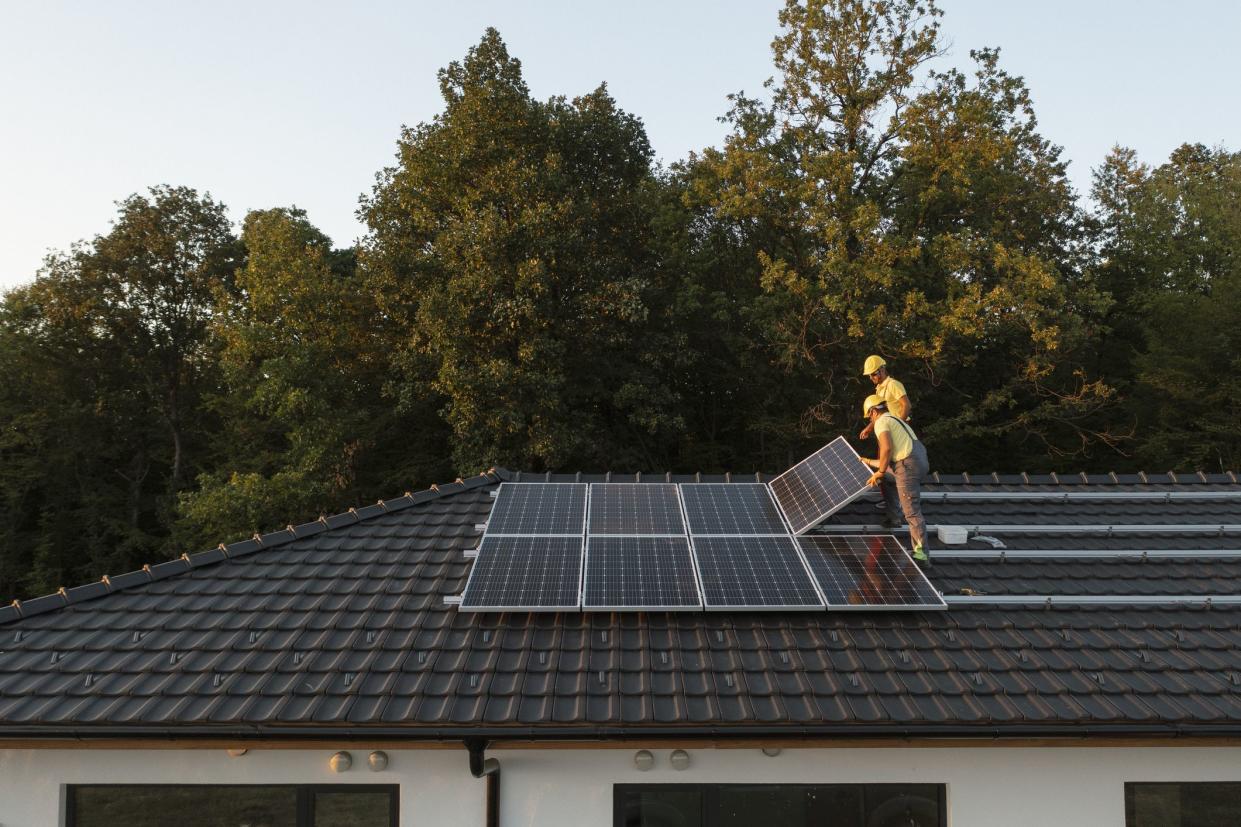 Two Professionalists Installing Solar Panels On A   Roof Of A Modern House.