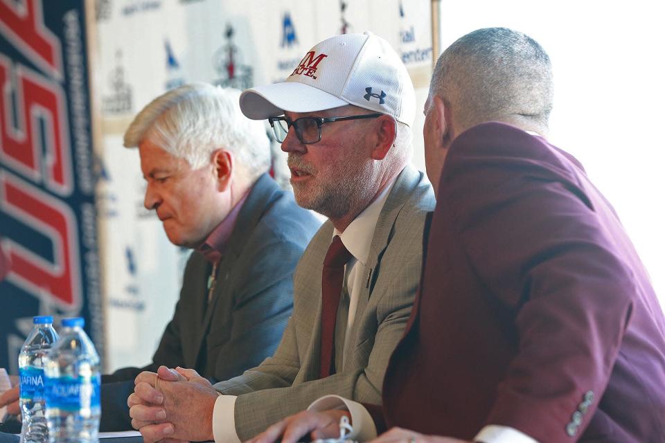 From the right, NMSU Athletics Director Mario Moccia whispers into the Aggie football coach Jerry Kill&#39;s ear as Moccia, Kill and NMSU Chancellor Dan Arvizu wait to address the media on Nov. 29, 2021.