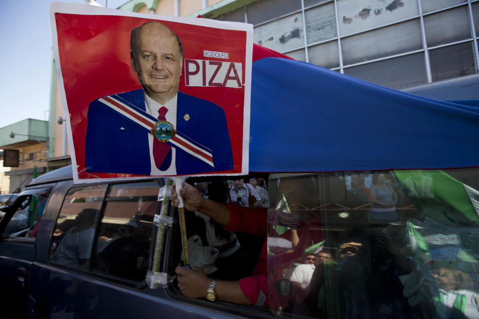 Un hombre sostiene un retrato de Rodolfo Piza, candidato presidencial del Patido Unidad Social Cristiana, desde un automóvil en San José, Costa Rica, el sábado 1 de febrero de 2014. (Foto AP/Moisés Castillo)