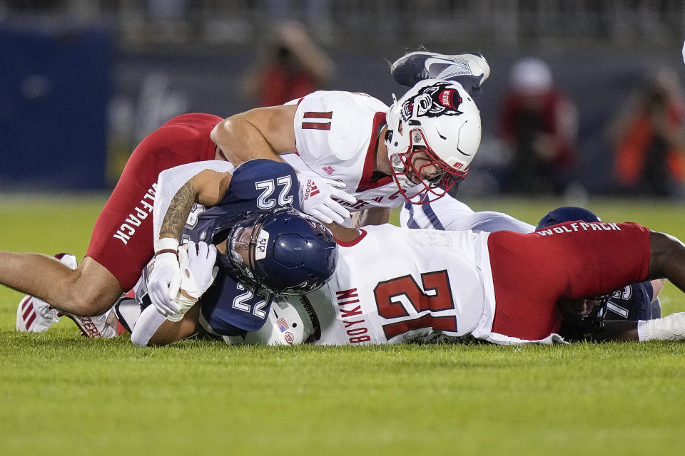 UConn running back Victor Rosa (22) is tackled by North Carolina State linebacker Payton Wilson (11) and defensive back Devan Boykin (12) during the first half an NCAA college football game in East Hartford, Conn., Thursday, Aug. 31, 2023. (AP Photo/Bryan Woolston)