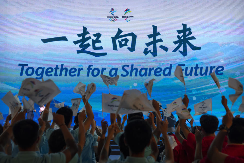 Participants cheer as the motto for the 2022 Beijing Winter Olympics and Paralympics is revealed at a launch ceremony in Beijing, Friday, Sept. 17, 2021. Organizers on Friday announced “Together for a Shared Future” as the motto of the next Olympics, which is scheduled to begin on Feb. 4 of next year. (AP Photo/Mark Schiefelbein)