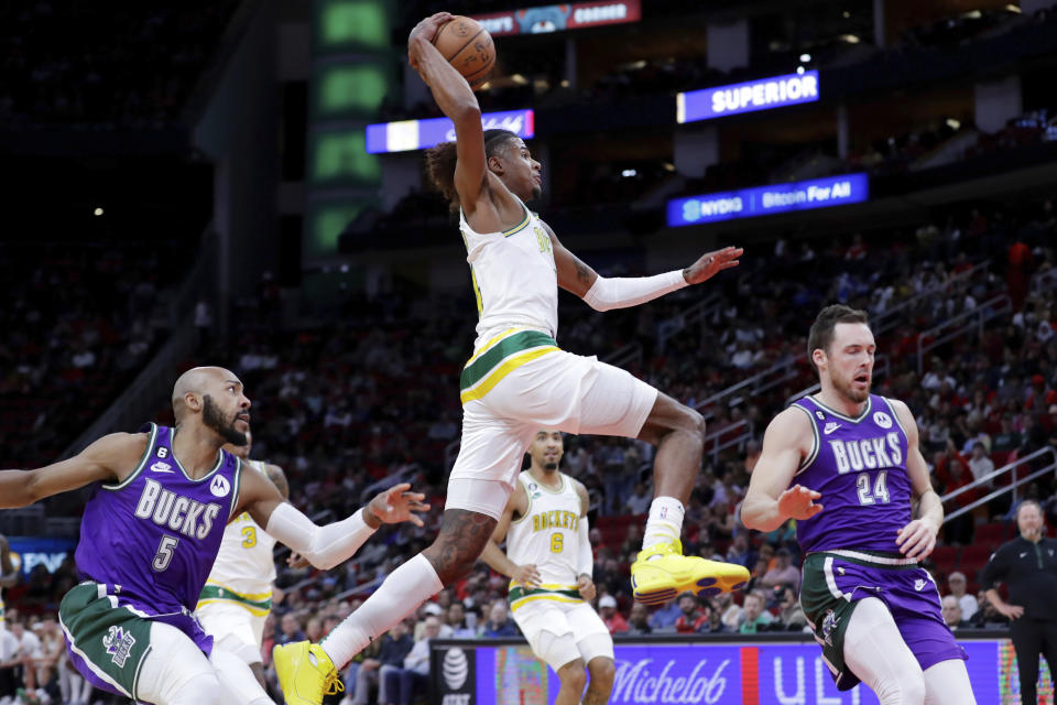 Houston Rockets guard Jalen Green, center, puts up a dunk between Milwaukee Bucks guards Jevon Carter (5) and Pat Connaughton (24) during the first half of an NBA basketball game Sunday, Dec. 11, 2022, in Houston. (AP Photo/Michael Wyke)