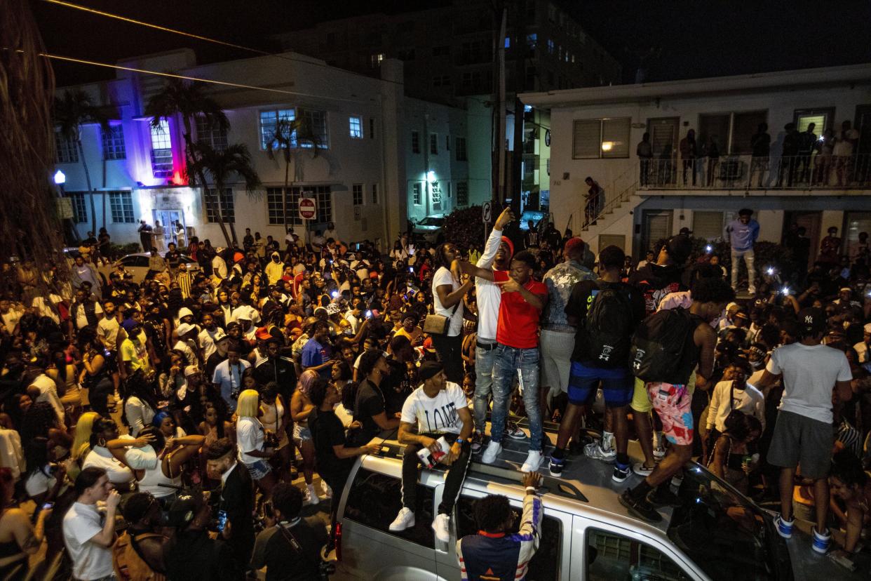 Crowds defiantly frolic in the street while a speaker blasts music an hour past curfew in Miami Beach, Florida, on March 21, 2021. (Daniel A. Varela/Miami Herald via AP)