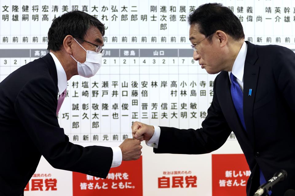 Japan's Prime Minister and ruling Liberal Democratic Party leader Fumio Kishida, right, fist bumps with former foreign minister and senior member of the party Taro Kono, at the party headquarters at the party headquarters in Tokyo, Sunday, Oct. 31, 2021. Japanese Prime Minister Fumio Kishida’s governing coalition is expected to keep a majority in a parliamentary election Sunday but will lose some seats in a setback for his weeks-old government grappling with a coronavirus-battered economy and regional security challenges, according to exit polls. (Behrouz Mehri, Pool via AP)