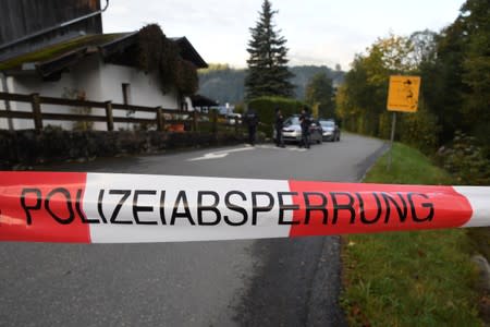 Police officers and rescue workers stand in front of a house where, according to police, five people were found dead in Kitzbuehel