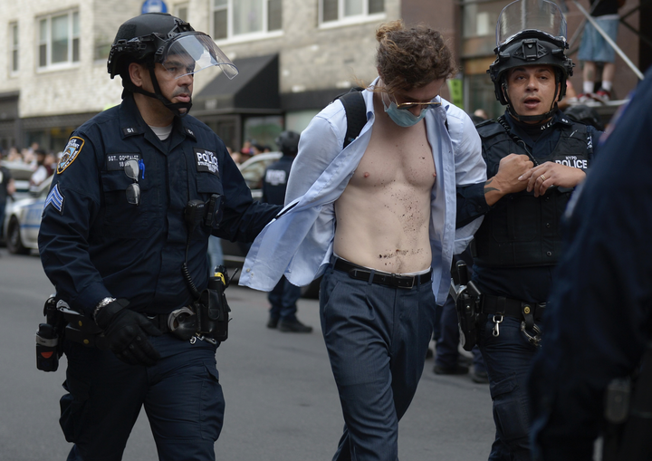 A man with an open shirt is arrested by police